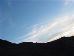 A photo of a mountain horizon, slanted such that the horizon is roughly level, but the clouds are askew